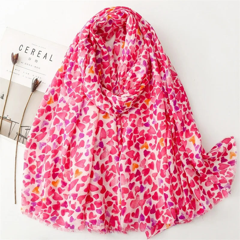 Foulard Femme Cœurs Envoûtants présenté sur fond blanc avec un magazine et des fleurs séchées