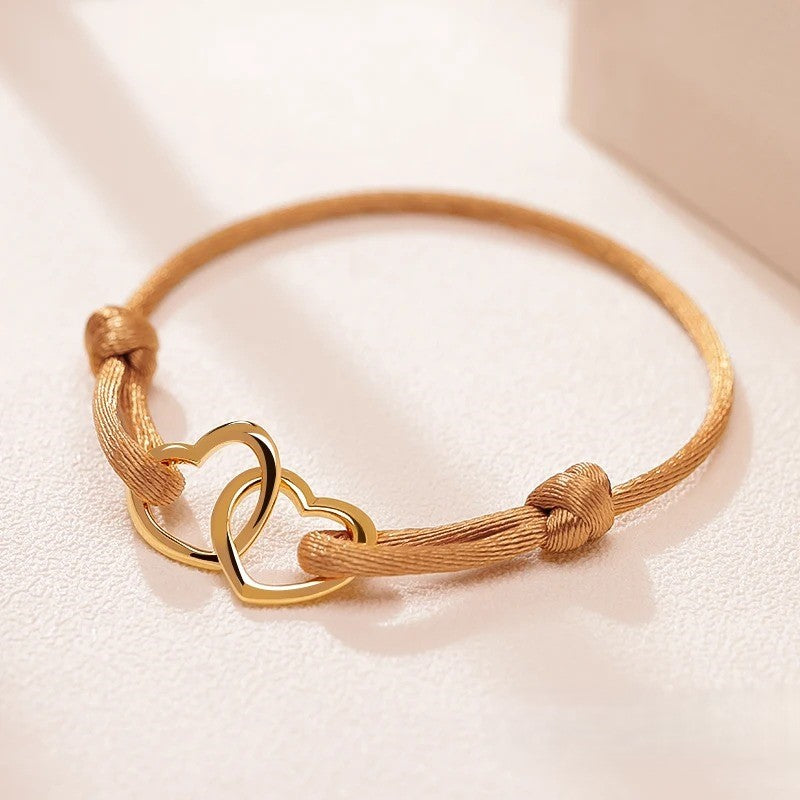 Bracelet Femme Double Cœurs et Cordon marron clair sur un tissu beige rose