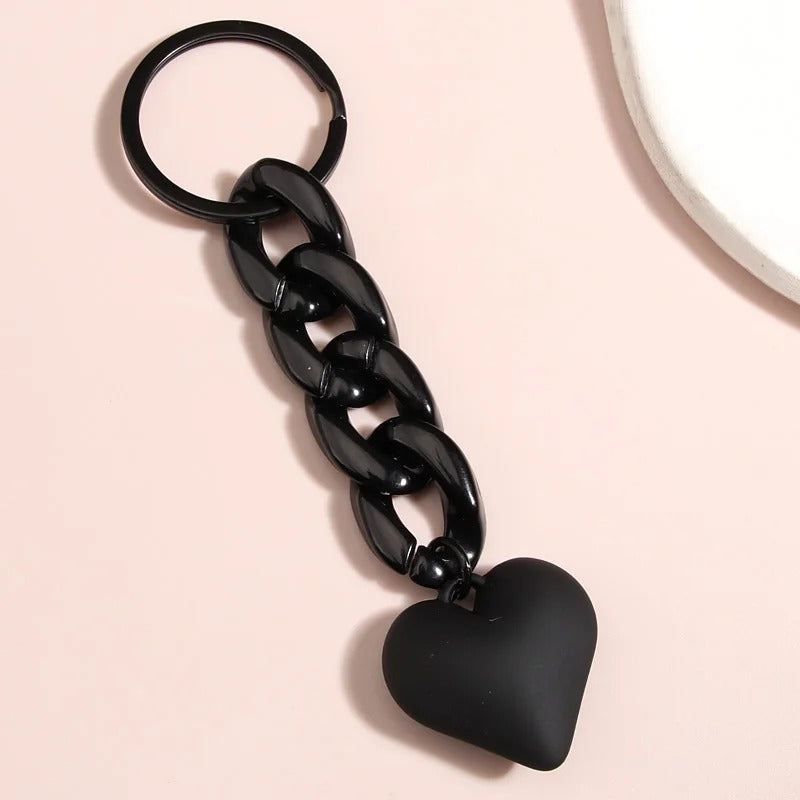 Porte Clé Chaine et Cœur Noir présenté sur fond rose pâle