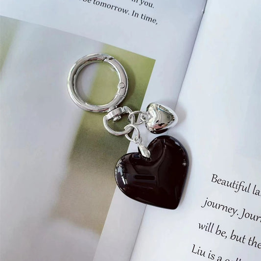 Porte Clé Cœurs Noir et Argenté présenté sur un magazine