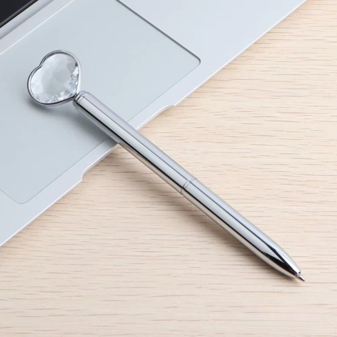 Stylo à Bille Sceptre en Forme de Cœur sur un fond beige et un ordinateur portable