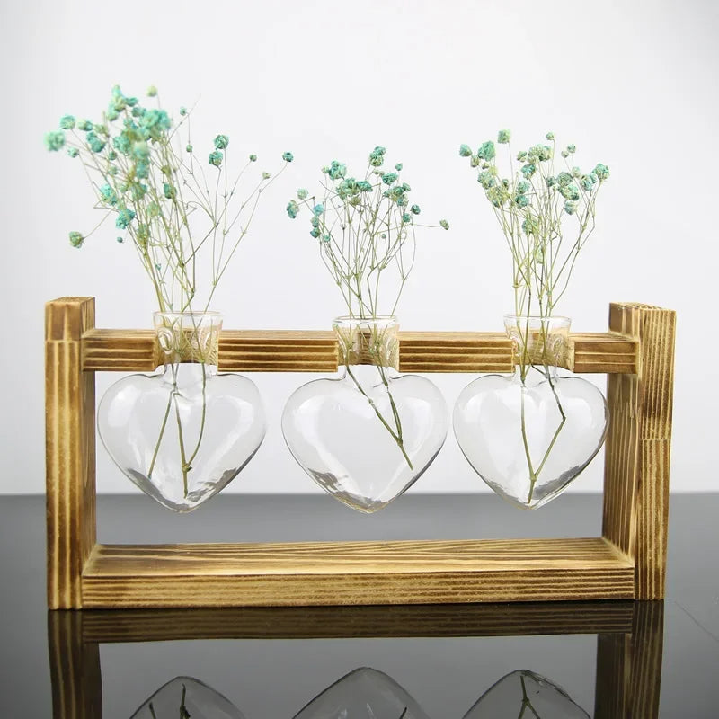 Vase Coeur en Verre Support en Bois sur fond gris avec des fleurs dedans